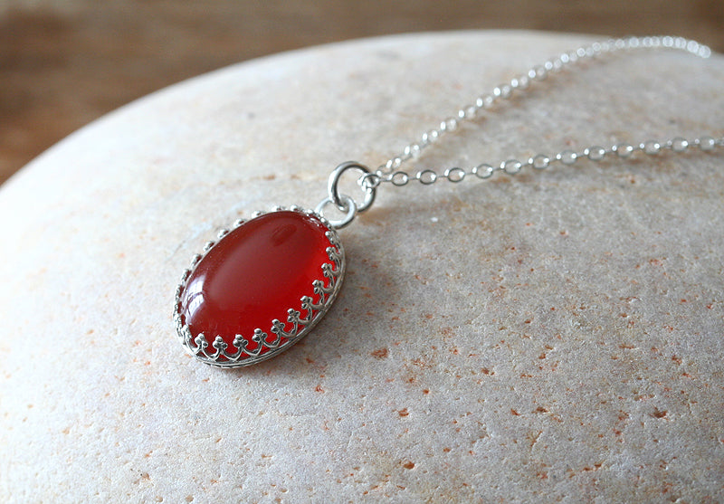 Ethical oval carnelian princess crown necklace. Sterling silver. On finger. Handmade in the US with sustainable silver.