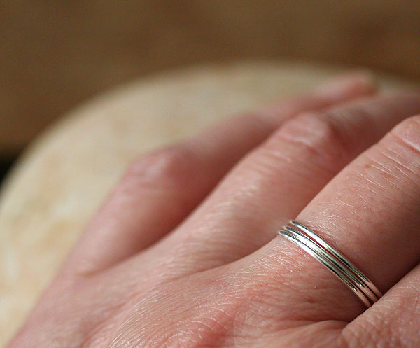 Thin stacking rings in sustainable sterling silver. Stacked on finger. Handmade in New Jersey, US.