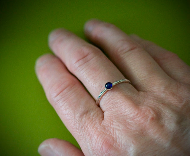 Ethical blue sapphire stacking ring in sterling silver on finger. Handmade in the US.