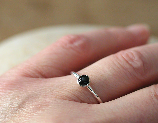 Small black onyx stacking ring on hand in all sizes. Sterling silver. Minimalist design. Handmade in the US with sustainable silver.