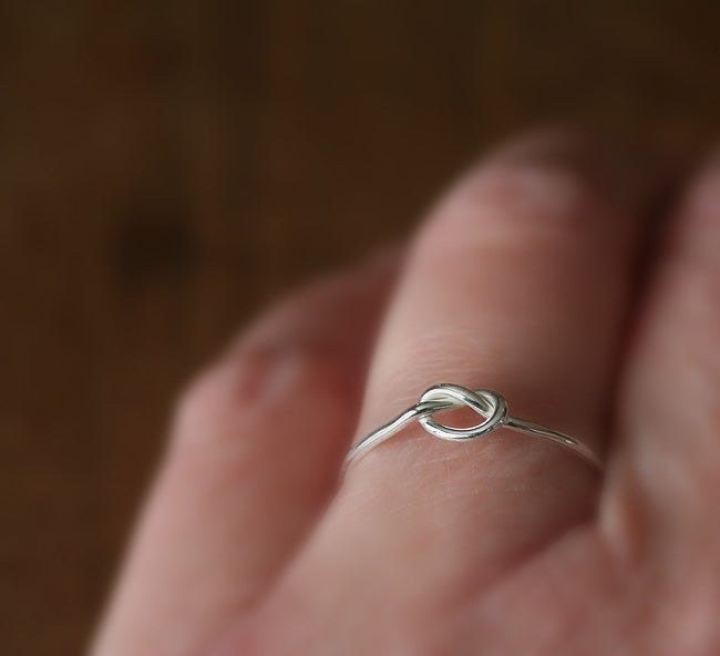 Knot love ring on finger in sustainable sterling silver