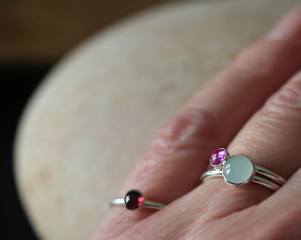 Pink sapphire, aquamarine, and garnet stacking rings on finger. Sterling silver. Handmade in the US with sustainable silver.